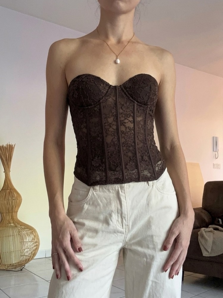 Corset en dentelle marron, porté par la même personne dans le même salon